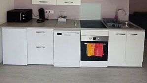A compact kitchenette with white cabinets, a built-in oven, a sink, and a coffee maker. - Apartment in the immediate vicinity of Château de Maintenon (Pierres)