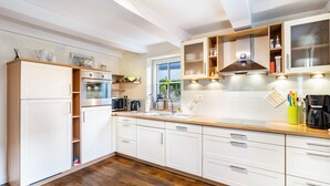 A modern kitchen with white cabinetry, a built-in oven, and a large window providing natural light.