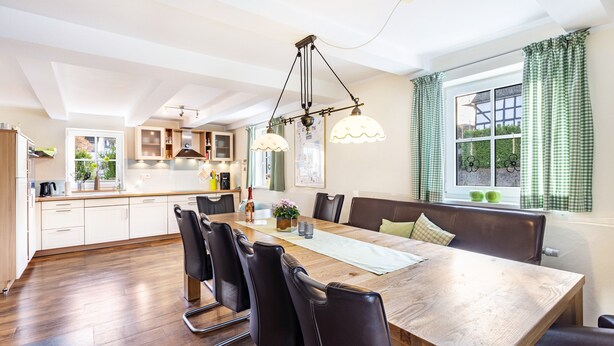 A modern kitchen with a dining area, wooden table, and chairs.