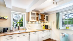 A modern kitchen with white cabinets, a wooden countertop, a coffee maker, and a radiator.