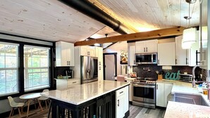 Une cuisine moderne avec des armoires blanches, des appareils en acier inoxydable et un grand îlot central.