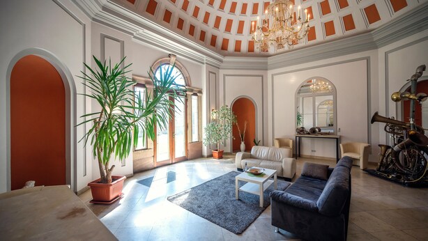 Uma sala de estar espaçosa com teto alto, um candelabro, uma grande planta em vaso, um sofá, uma mesa de centro e uma moto.