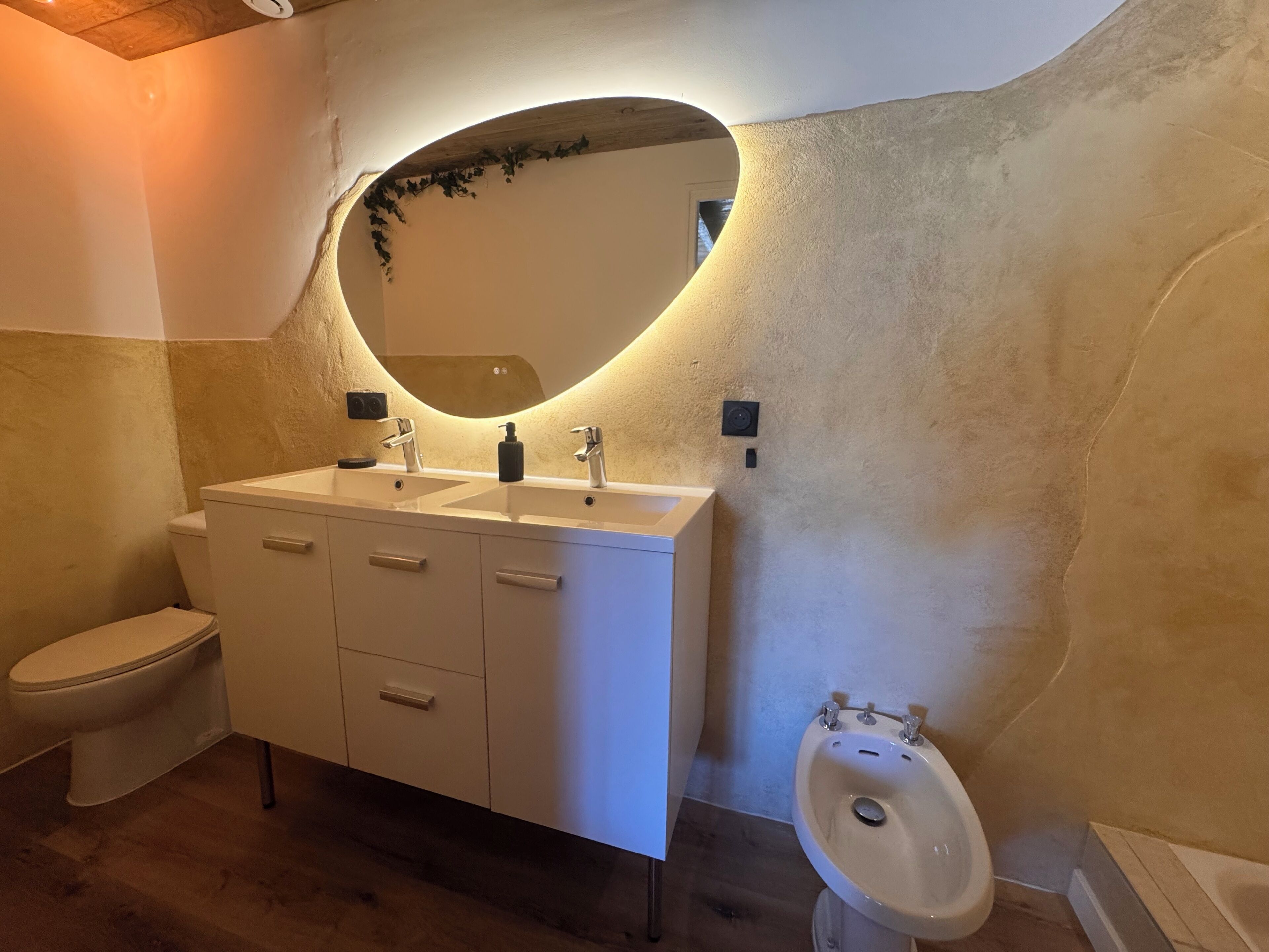 Une salle de bain avec un meuble-lavabo blanc, deux vasques, des toilettes et un bidet.