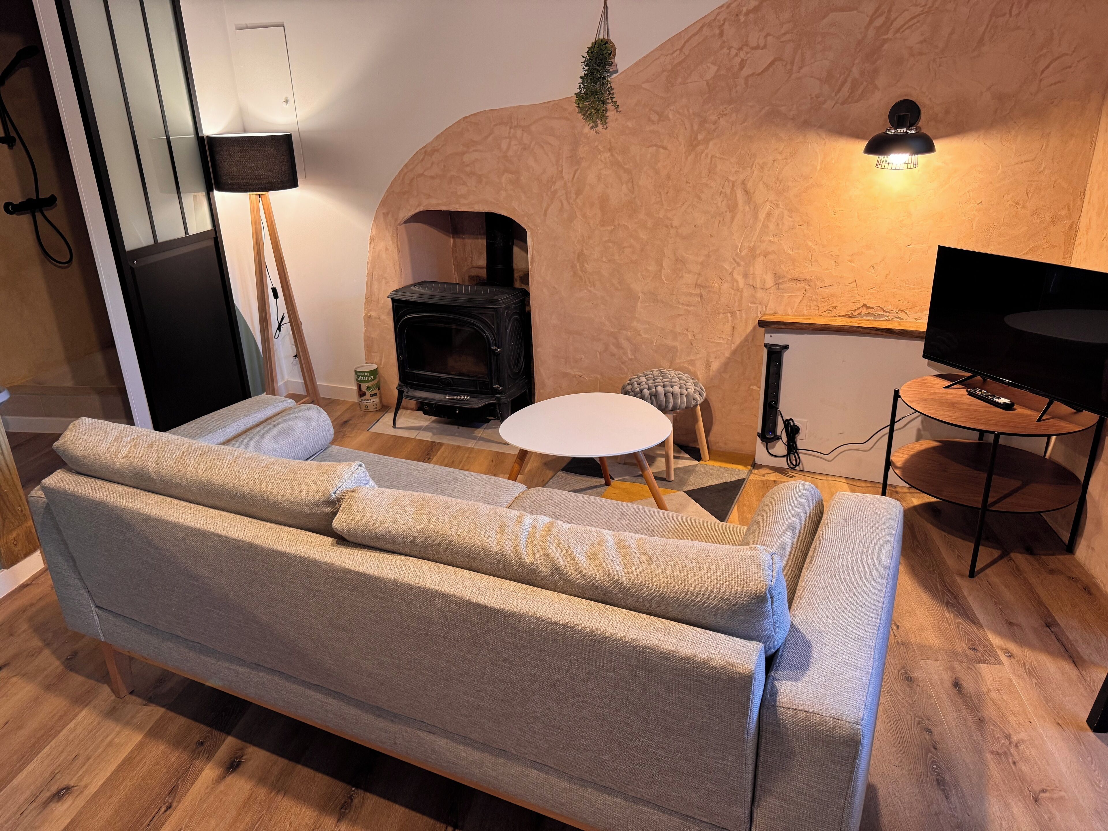 A cozy living room with a sofa, a small round table, a television, and a fireplace.