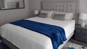 Une chambre à coucher avec un grand lit, deux tables de chevet et une petite table d’appoint.
