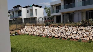 Un quartier résidentiel moderne, avec des immeubles à plusieurs étages, une pelouse bien entretenue et un mur en pierre.