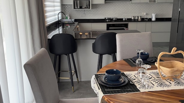 Une cuisine moderne avec des meubles blancs, un îlot central et des luminaires suspendus.