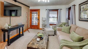 Un salon comprenant un téléviseur à écran plat, une console, une table basse, un canapé et une lampe.