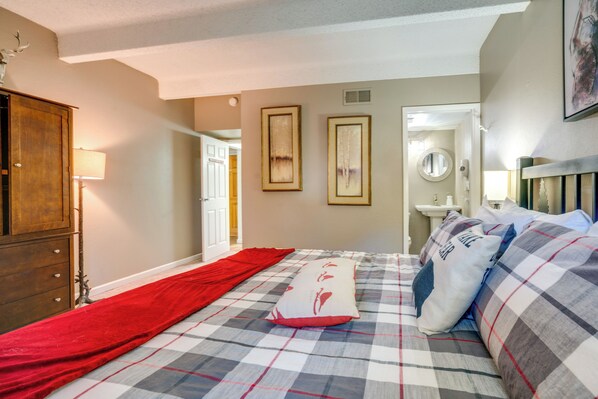 A bedroom with a checkered bedspread, a red runner, a wooden wardrobe, and two framed pictures on the wall. - Ski Copper Mountain! Alpine-Chic Condo w/ Hot Tub (Frisco)
