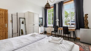 Une chambre d’hôtel avec un lit, un bureau, une chaise et une grande fenêtre avec des rideaux.