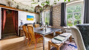 Un espace repas comprenant une table, des chaises et des plantes suspendues.