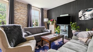 Un salon comprenant un canapé, un fauteuil, une table basse et un téléviseur à écran plat.