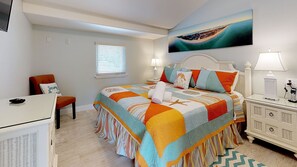 Une chambre à coucher avec un lit, une chaise, une table de chevet, une lampe et un tableau au mur.