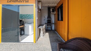 Ein kleiner Außenbereich mit einer Küche, einem Grill, einer Waschmaschine und einem Tisch mit Stühlen.