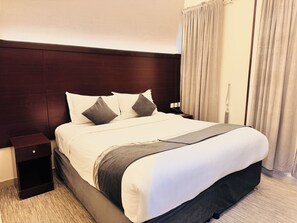 A hotel room with a large bed, a nightstand, a bedside table, and a curtain. - Rowaa Makarem (Makkah)