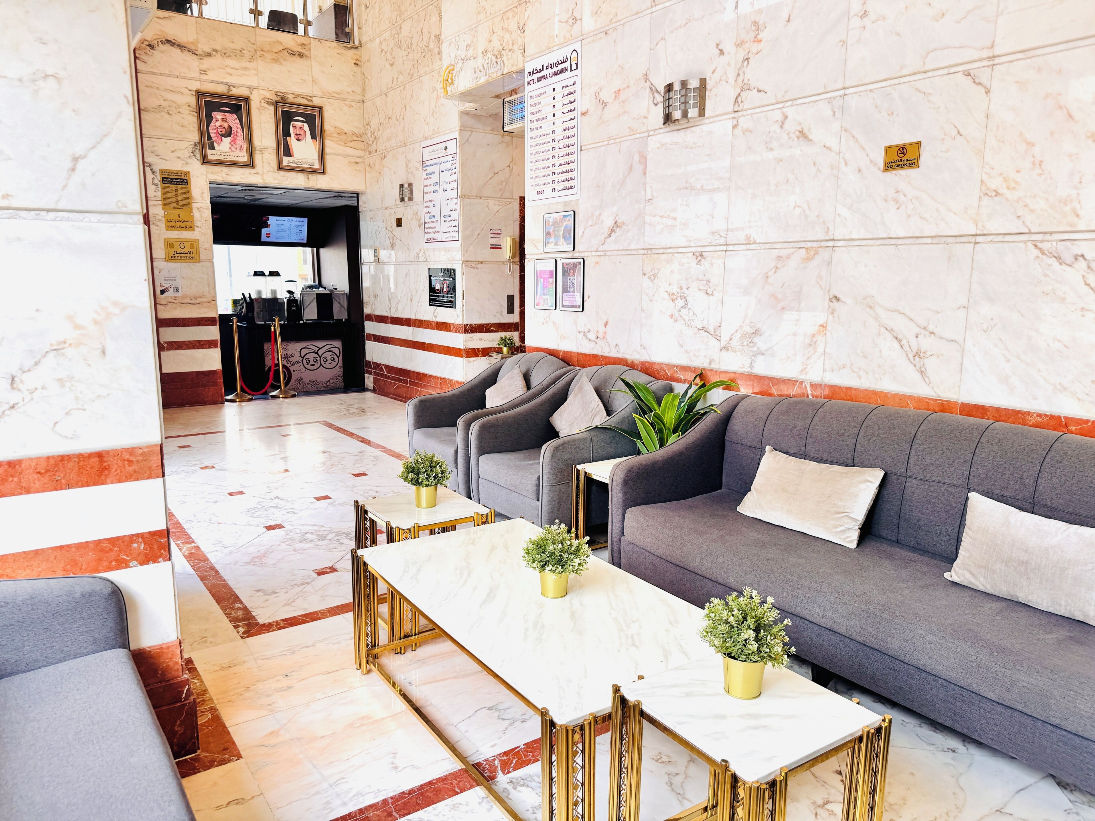 A hotel lobby with marble flooring, a reception desk, a sofa, and a coffee table.