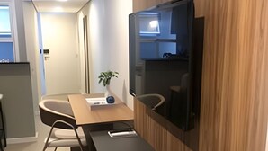 A modern kitchen with a wooden accent wall, a built-in TV, a dining table with chairs, and a small plant. - Belgravia  (Porto Alegre)