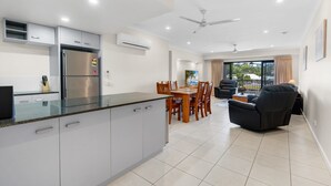 Una cocina moderna con una isla integrada, comedor con mesa y sillas, y zona de estar con sofá.