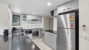 Una cocina moderna con electrodomésticos de acero inoxidable, armarios blancos y encimera de granito.