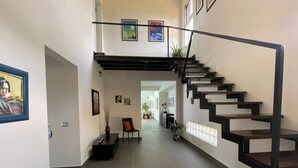 Un interior moderno con una escalera, un área de descanso y obras de arte en las paredes.