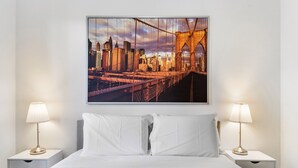 A hotel room with a large bed, two bedside tables with lamps, and a cityscape painting on the wall. - Chic 2-bed Apartment Near Albert Park (Melbourne)