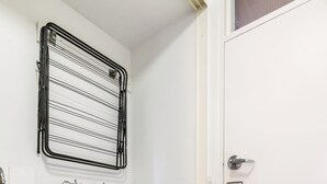 A compact laundry area with a washing machine, a sink, and a drying rack. - Chic 2-bed Apartment Near Albert Park (Melbourne)
