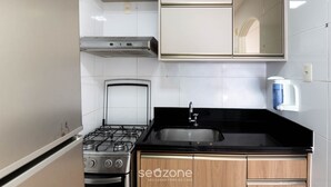 A kitchen with a gas stove, a sink, and a coffee maker. - Apt w/ Balcony and sea View in Guarapari Cmd0311 (Guarapari)