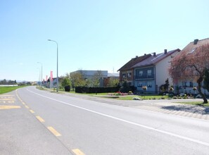 A residential street with houses, a clear sky, and a road with yellow markings. - Apartments Ro Ma (Pozega)