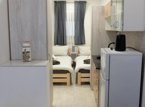 A compact bedroom with two single beds, a small kitchenette, and a refrigerator. - Apartments Ro Ma (Pozega)