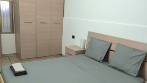 A bedroom with a large bed, a wardrobe, a nightstand, and a mirror.