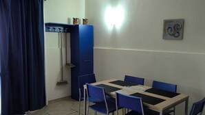 A small dining area with a table and chairs, a blue cabinet, and a broom.