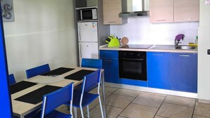 A compact kitchen with a dining area, featuring a microwave, oven, and sink.