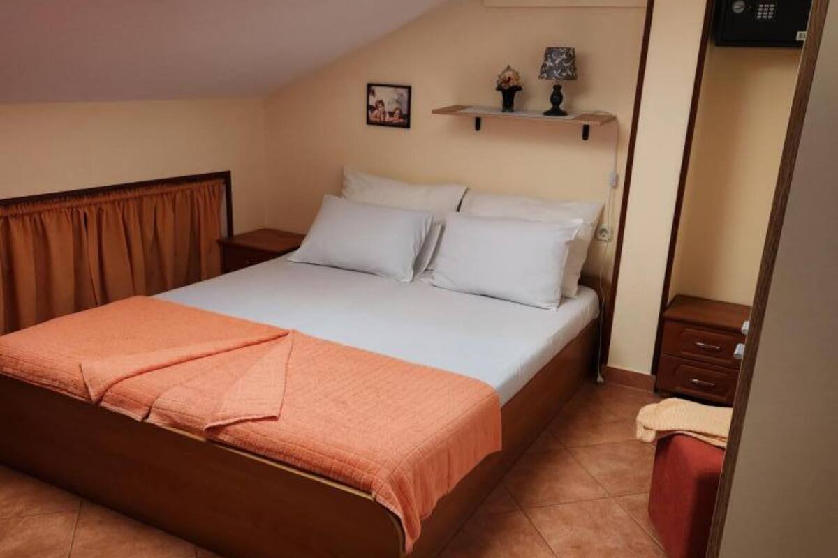 Ein Schlafzimmer mit einem Bett, einem Nachttisch, einer Ablage mit Dekoration und einem roten Sessel.