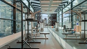 Une salle de sport moderne dotée de divers appareils d’entraînement, de grandes fenêtres et offrant une vue sur le paysage urbain.