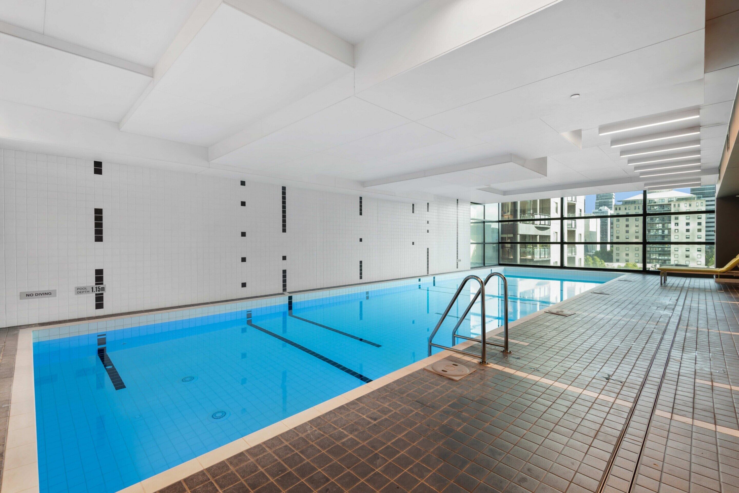 Une piscine intérieure à l’eau d’un bleu limpide, avec des murs et un sol carrelés.