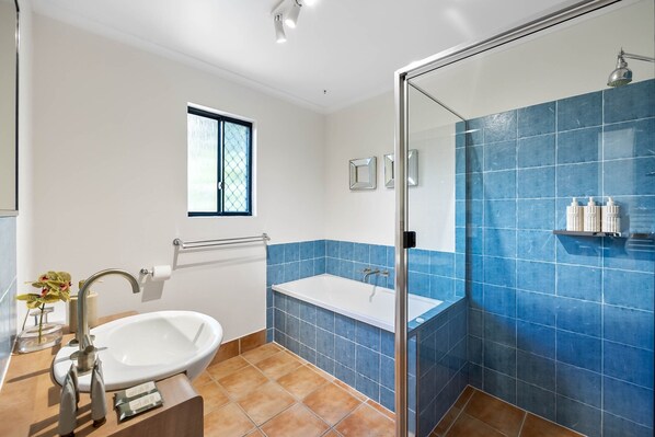 Un baño con bañera, lavamanos y cabina de ducha de vidrio.
