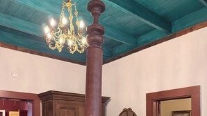 Un dormitori amb un llit amb cortines, un penjallum, mobles de fusta i un mirall gran.