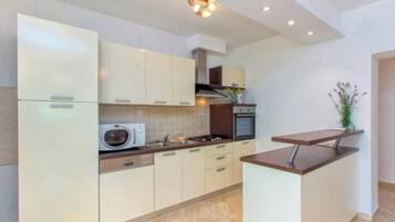 A modern kitchen with white cabinetry, a built-in microwave, a stove, and a small island with a countertop.
