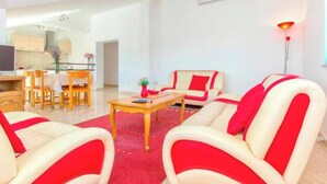 A modern living room with a red and white sofa set, a wooden coffee table, and a dining area with a table and chairs. - Villa Dalmacija (Drnis)