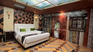 Ein Hotelzimmer mit einem großen Bett, einem Nachttisch, einem Schreibtisch und einem Kleiderschrank.