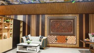 A room with a sofa, a coffee table, a decorative wall panel, and a ceiling with a floral pattern.