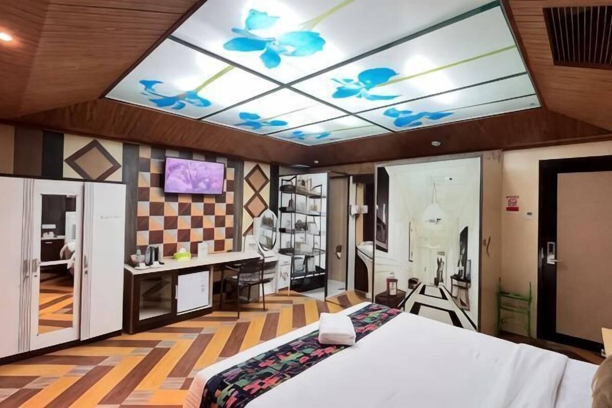 A hotel room with a bed, desk, wardrobe, and a television.