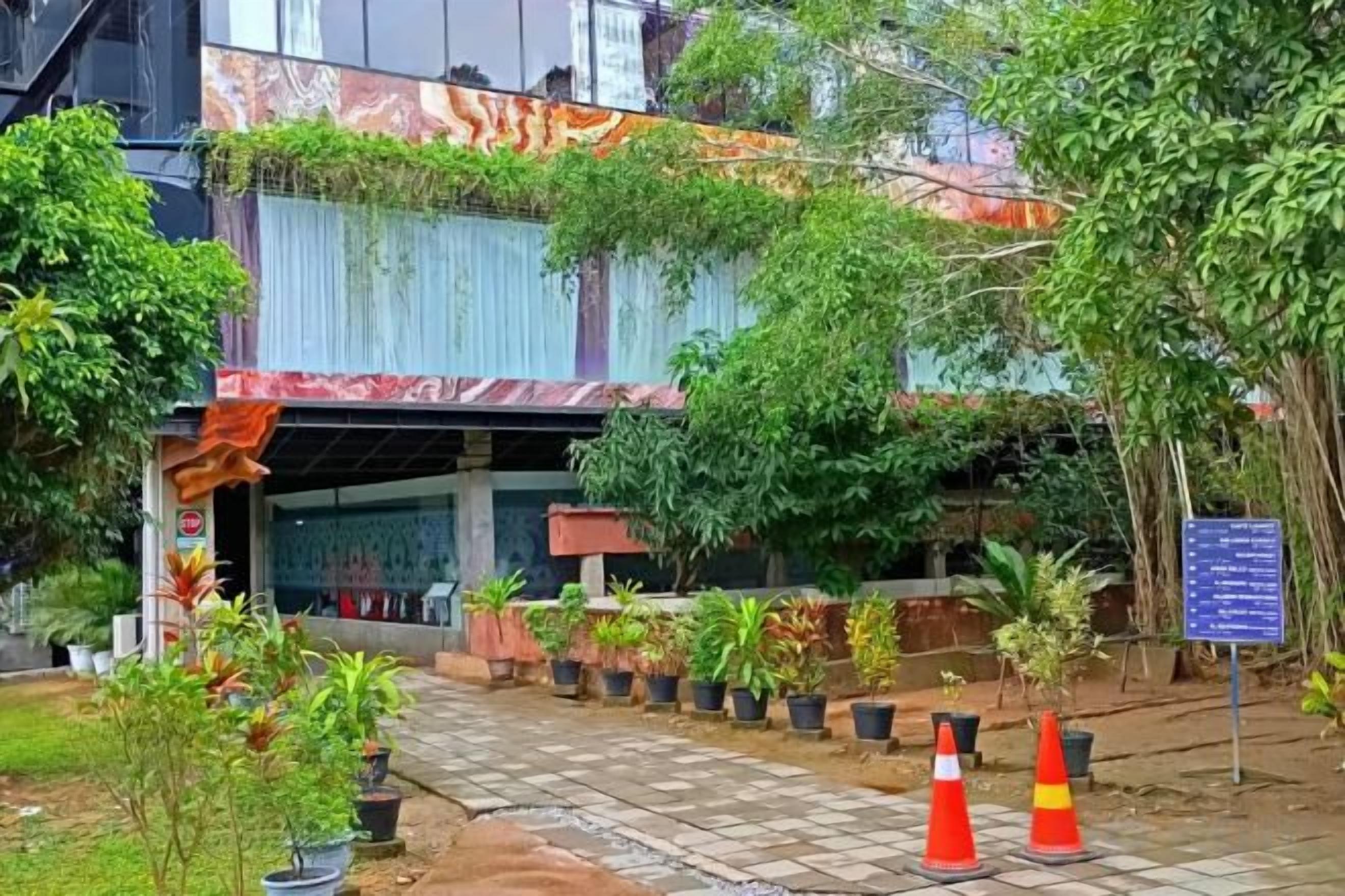 A building with a covered entrance, potted plants, and a paved pathway leading to the entrance.
