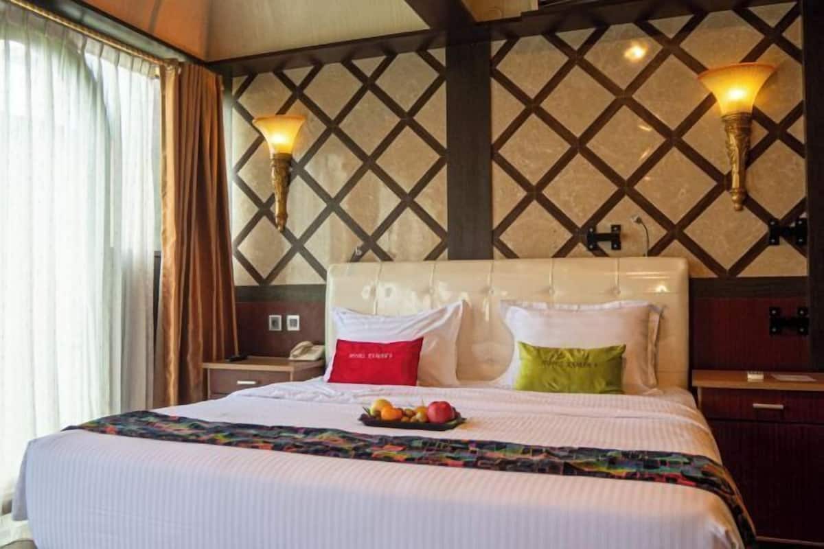 A hotel room with a bed, two wall-mounted lamps, a nightstand, and a bedside table.
