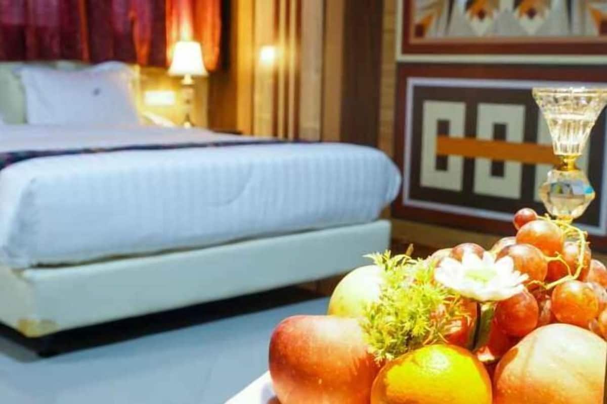 A hotel room with a bed, a bedside table with a lamp, and a decorative wall piece.