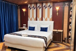 A hotel room with a large bed, two bedside tables, a nightstand, a wall-mounted lamp, and a patterned wall design. - Qubah 9 Hotel kendari (Kambu)