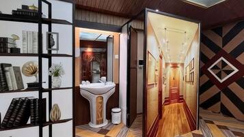 A hotel corridor with a bookshelf, a sink, and a patterned floor.