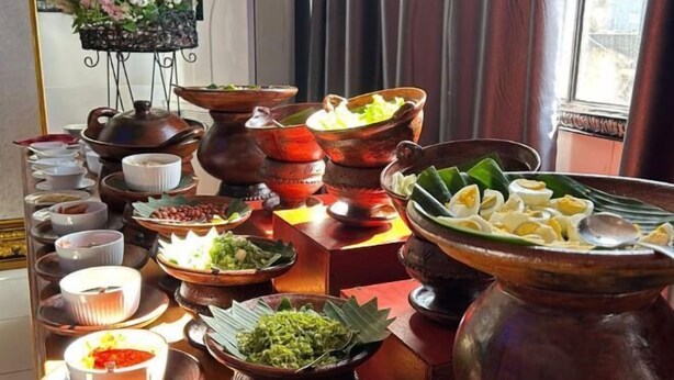 Verschiedene Gerichte und Besteck sind auf einem Tisch angerichtet, vermutlich für ein Buffet oder ein gemeinsames Essen.