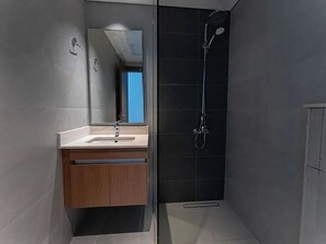 A modern bathroom with a sink, mirror, and shower.