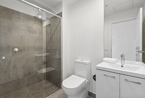 A modern bathroom with a glass-enclosed shower, a white toilet, and a sink with a mirror. - Bright City-view Retreat in the Heart of Preston (Melbourne)